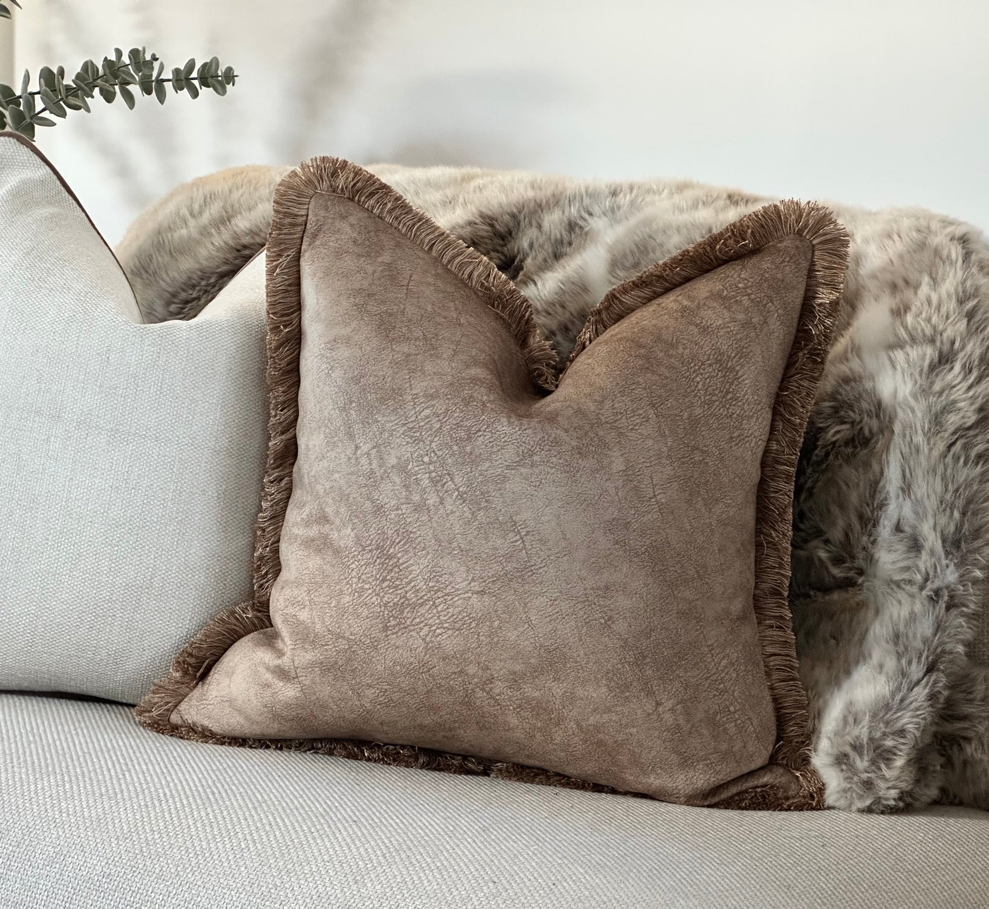 Beige Cushion with fringe trim on a neutral sofa, styled with a faux fur throw for a cosy, rustic aesthetic