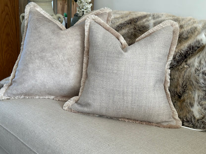 A bespoke designer cushion in a soft grey with taupe beige tones, textured weave and luxury fringe trim.