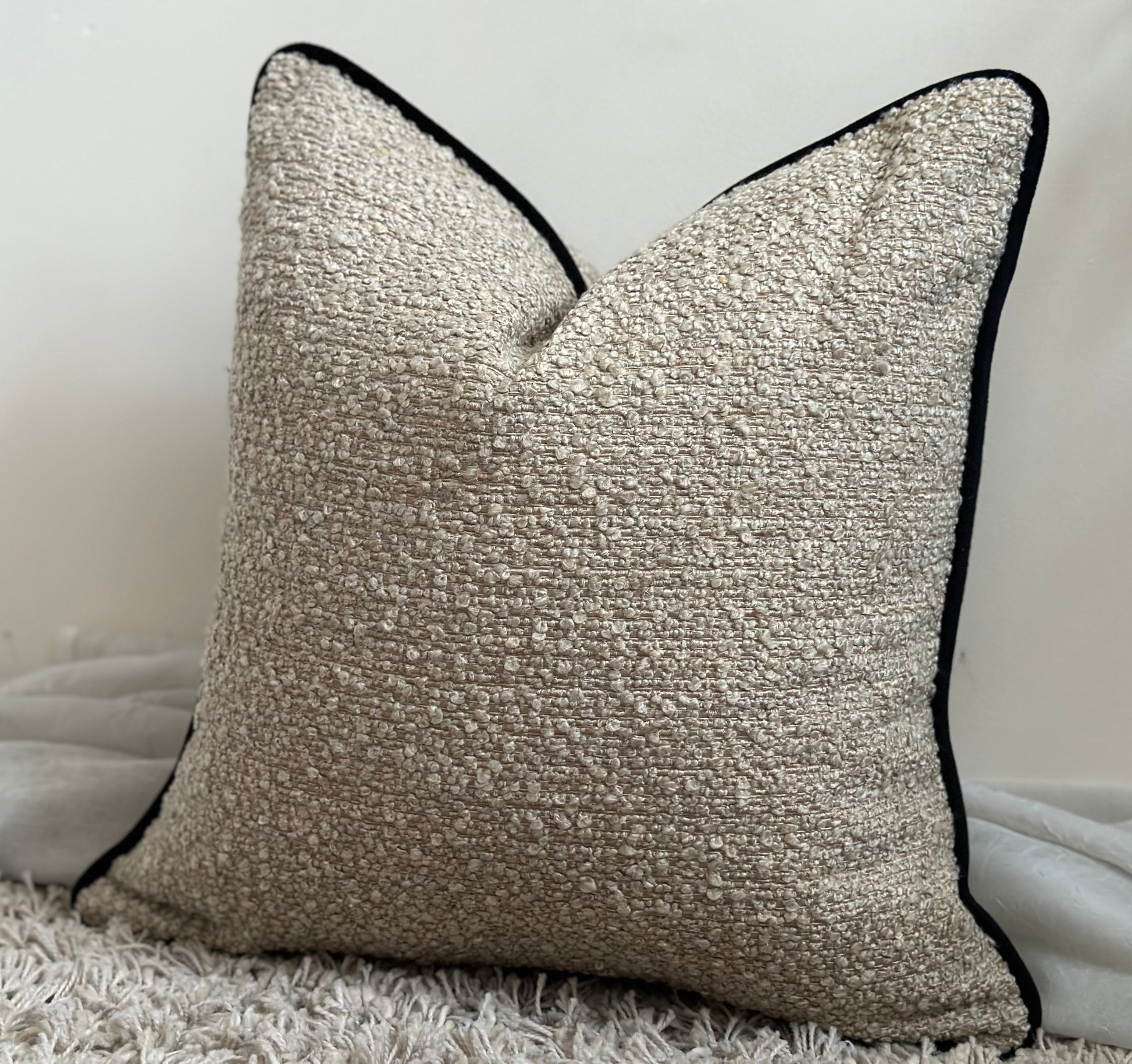 Modern pillows, neutral beige textured boucle with a black piped edge