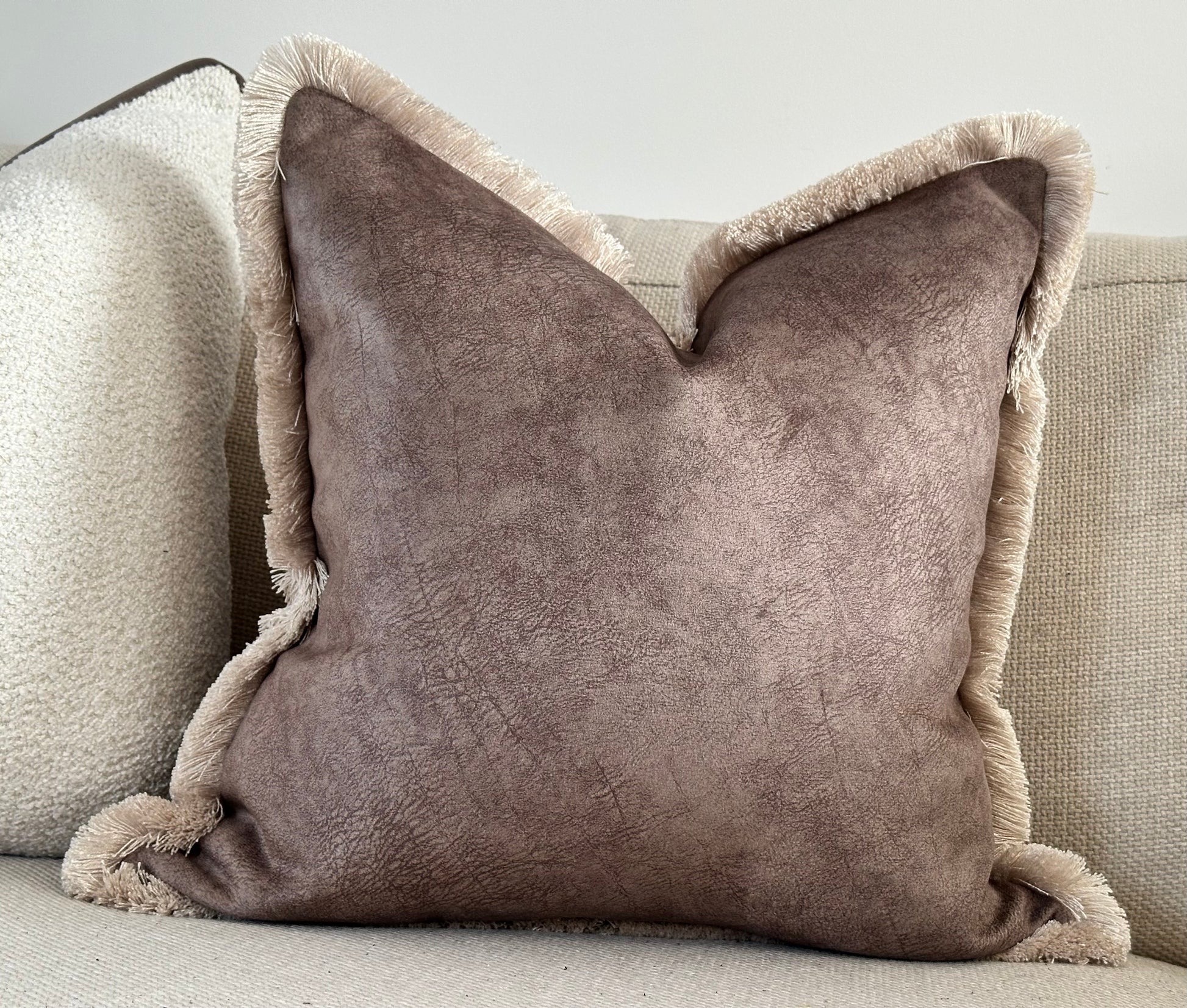 Modernd textured brown cushion with frilly trim.