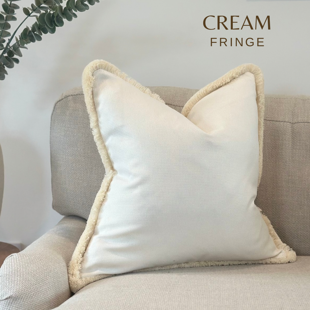 A light white cream pillow with a fringe that best compliments neutral home decor