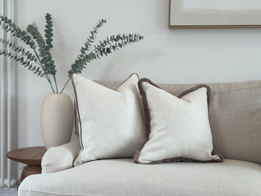 A light ivory cream throw pillow with a plain fabric on a matching light-colored sofa.  Fringing or a piped edge are available in all custom sizes.