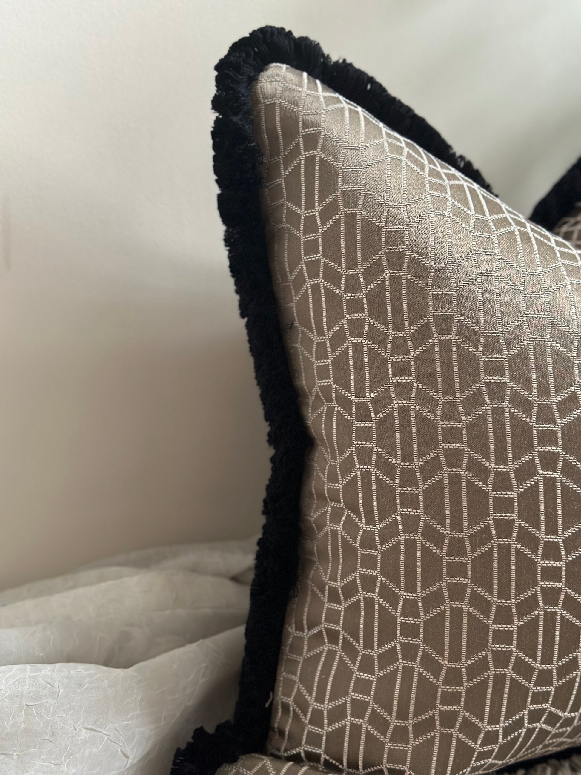 An image of a beautiful decorative pillow in a taupe colour with a black fringing