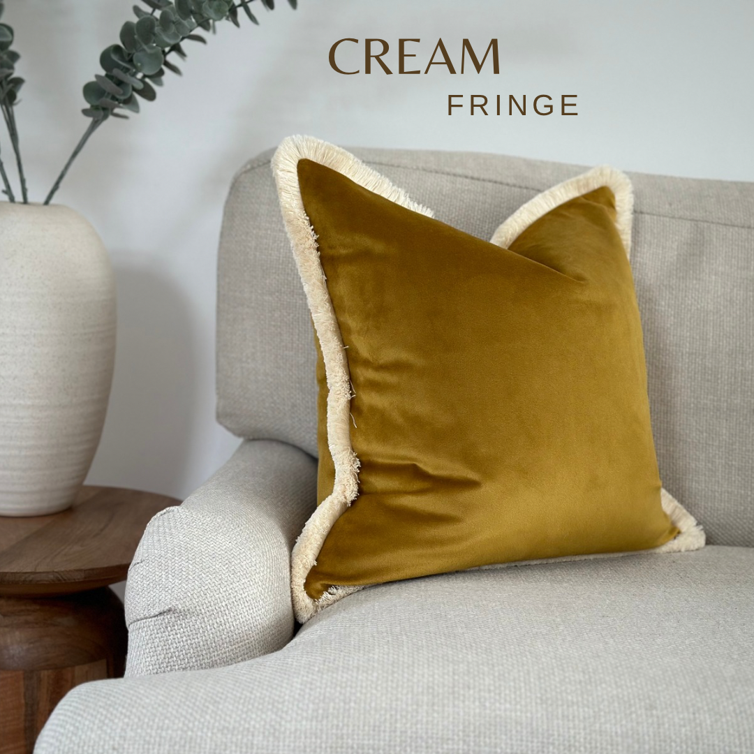 A luxury Mustard gold velvet cushion with cream fringe trim.