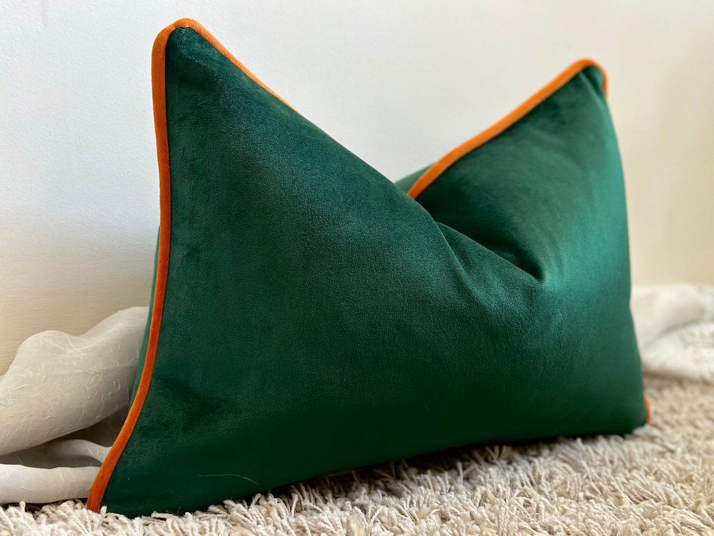 green pillow with orange piping trim