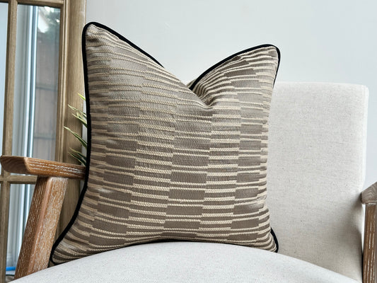 Textured beige taupe pillow with black contrast piping.