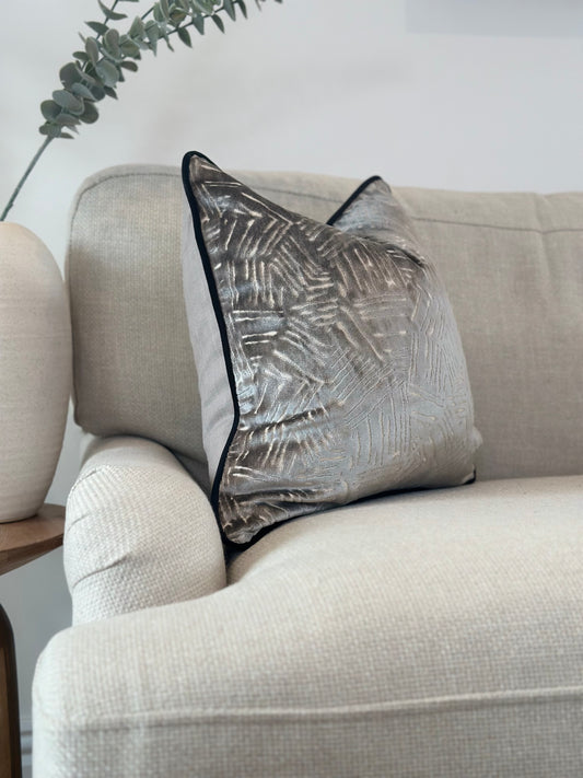 A modern grey velvet pillow with an abstract pattern and a black contrasting piping. Small, medium, large sizes.