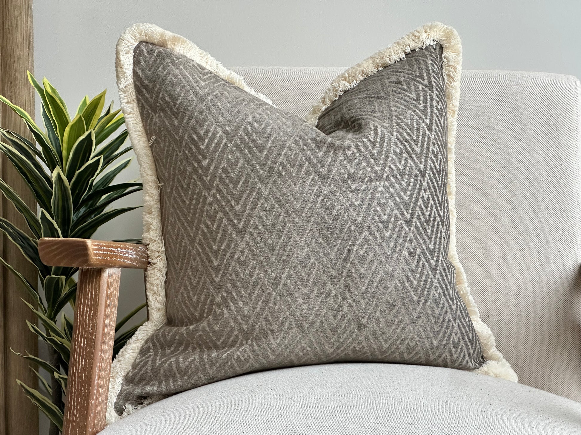 Modern grey pillow with cream fringed edge.