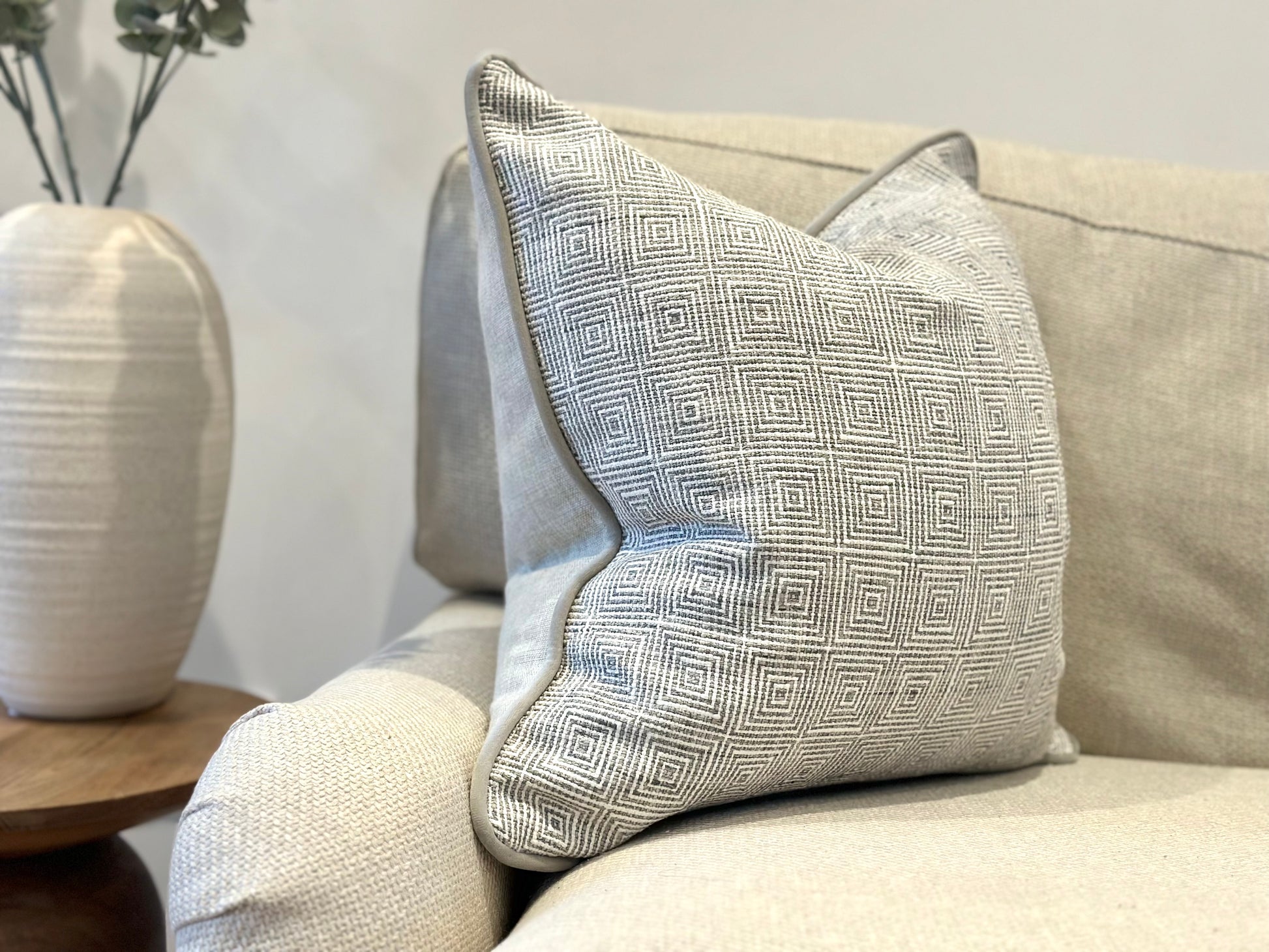 A modern luxury light grey cushion with a squared geometric pattern.